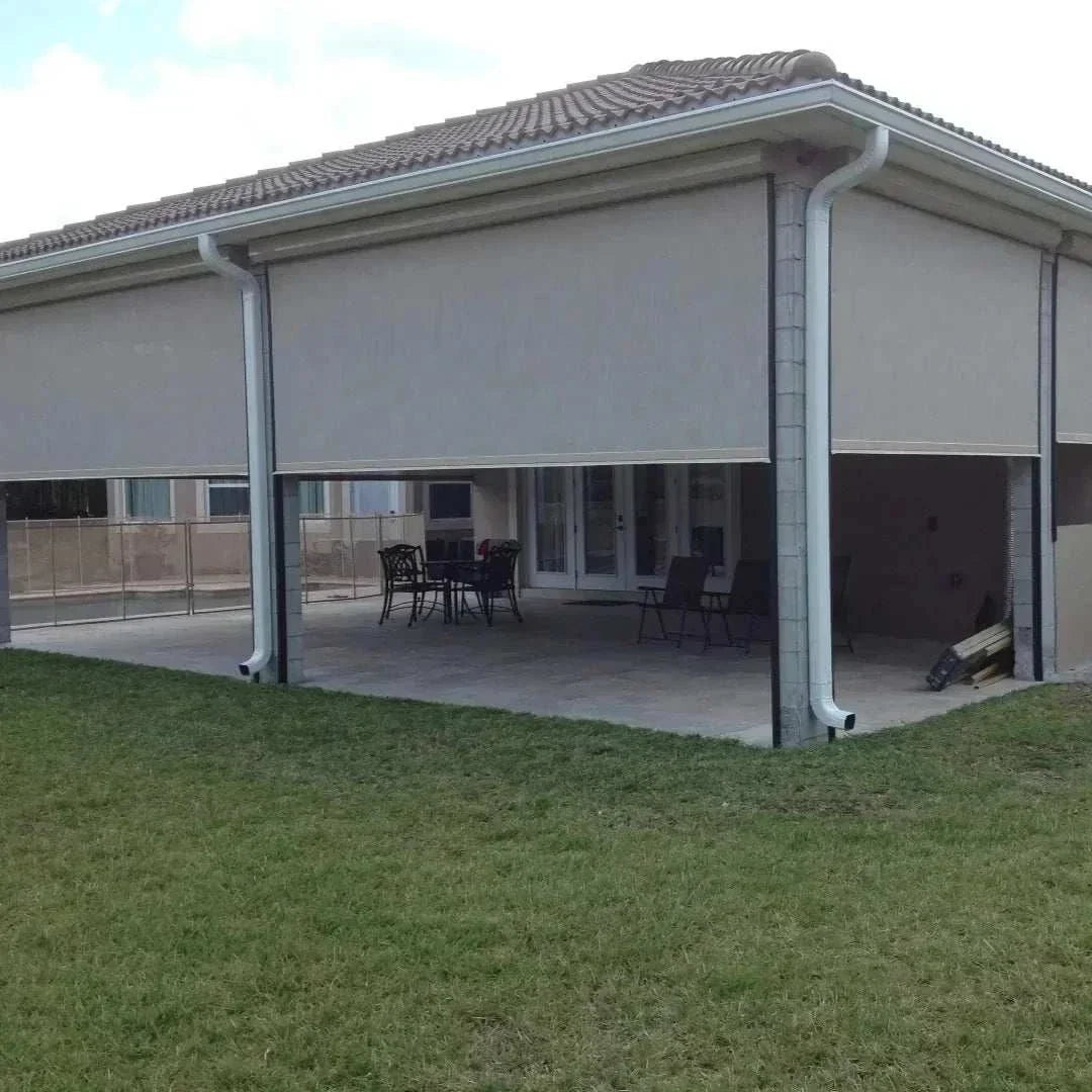 Motorized patio and garage screens installed on a modern home exterior providing sun and bug protection